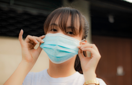Image of woman with bangs putting on medical mask