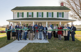 A photo of County Executive Calvin Ball and attendees cutting the ribbon in front of Hebb House to open the County's new Office of Agriculture.