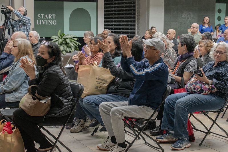 A diverse group of seated audience members clapping