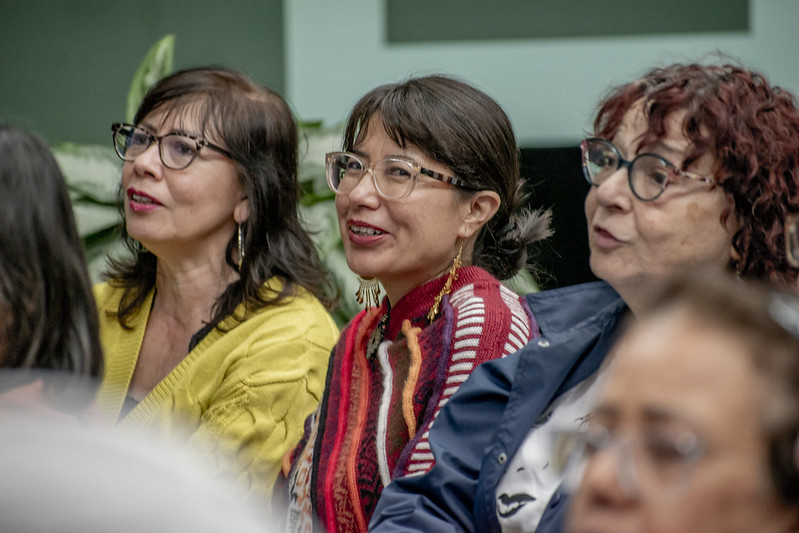 Three women audience members watching the performance. They have dark hair and glasses.