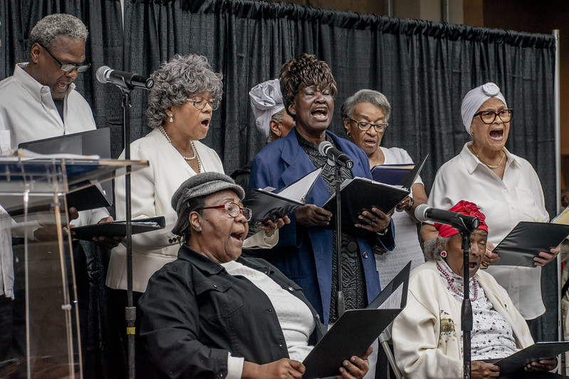 6 members of the Bain Gospel Choir singing holding their song books