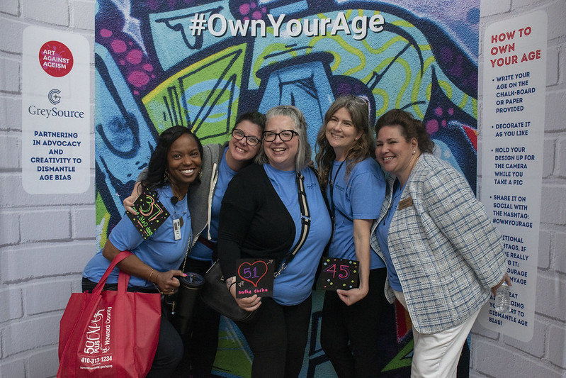 Group shot of 5 female staffing posing for photo at own your age photobooth