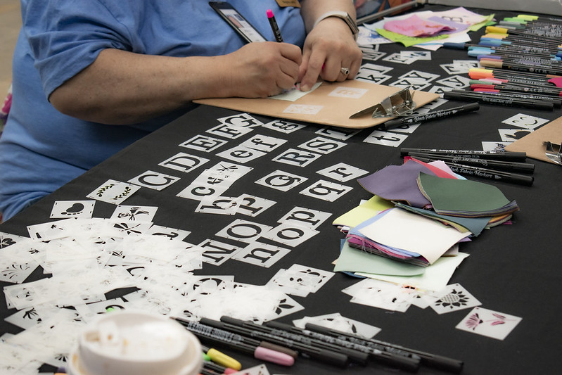 Photo of table with quilting squares and stencils and someone's handing drawing.