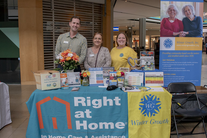 Group shot of the right of home staff in front of their vendor table. one male and two female.