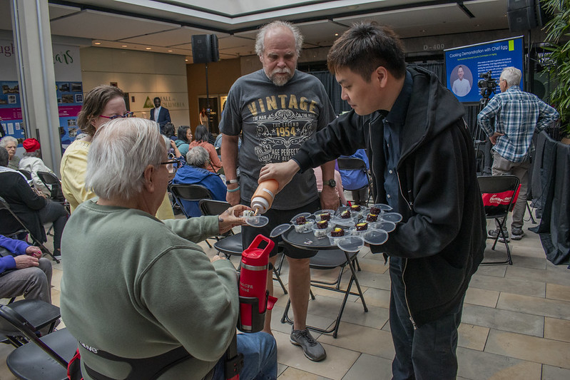 Asian man handing out sushi samples to seated guest