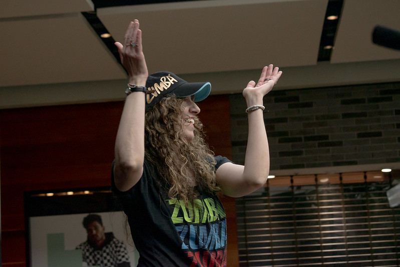 Zumba instructor smiling with her hands up.