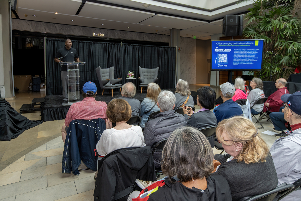View facing the stage of seated participants and Calvin Ball speaking