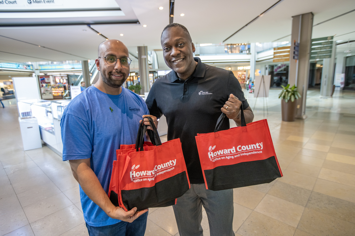DCRS staff member posing with County Executive Calvin Ball holding event bags with OAI logo