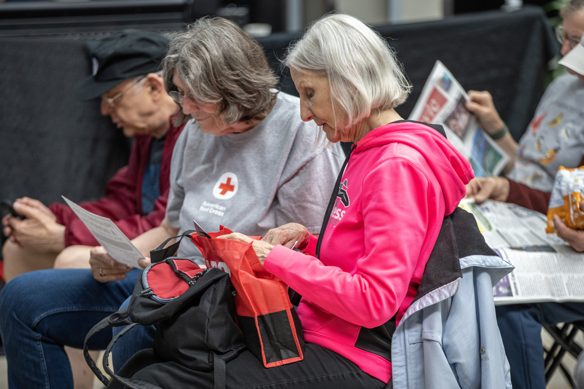 Two older adult white females sitting in audience reading materials.