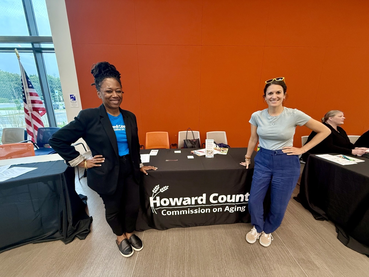 Two female commission on aging member posing by resource table