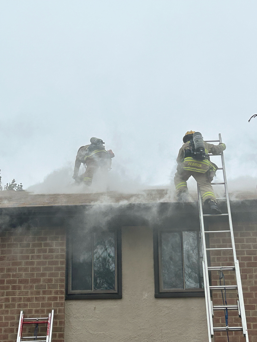 Firefighters on top of apartment roof, smoke showing