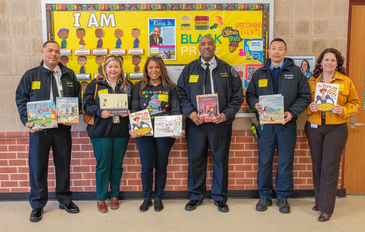 Fire personnel holding books in a school for Read Across America