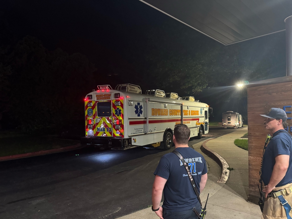 Firefighters stand outside building with medical bus