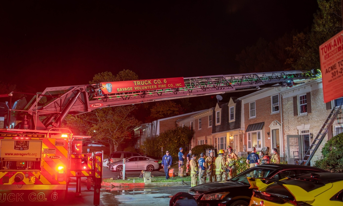 Ladder truck extended on top of townhome which was on fire, smoke visible