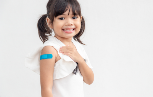 Young girl with pigtails shows the band-aid on her upper arm