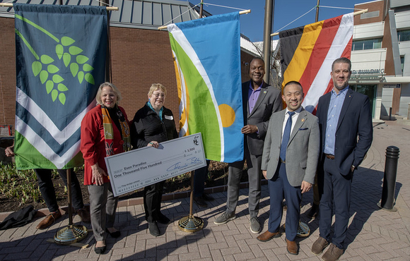 A photo of County Executive Calvin Ball holding up the new Howard County flag with flag designer and Ellicott City resident, Ms. Esen Paradiso.