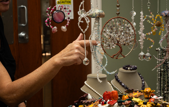 Handcrafted beaded art hanging with a person touching one of the items