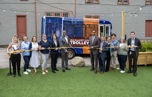 A photo of County Executive Calvin Ball and attendees preparing to cut the ribbon on the County's new pilot Old Ellicott City Trolley.