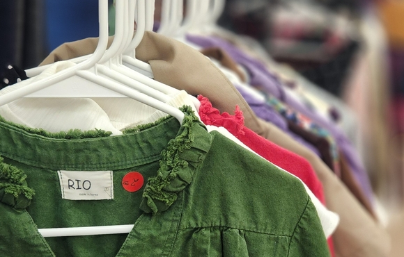 Clothes hanging on rack with hangers. First item is olive green shirt.