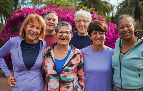Group of 6 older adults including 2 men and 4 women smiling in fitness clothes.