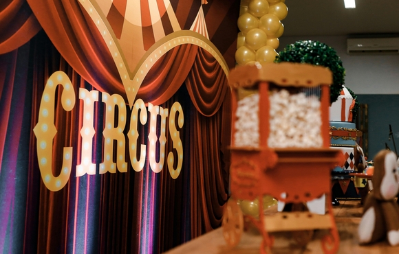 Maroon curtain with sign that says circus and a mini popcorn cart.