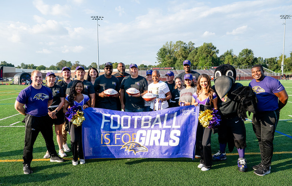A photo of County Executive Calvin Ball with members of the Baltimore Ravens and Howard County Public School System during a press conference announcing girl flag football is coming to all  Howard County high schools.