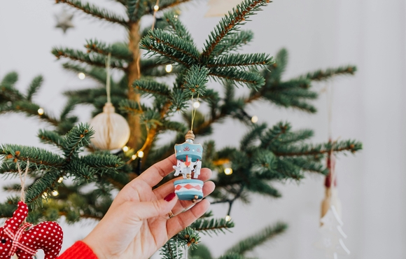 Arm reach out and touching ornament on a Christmas tree.