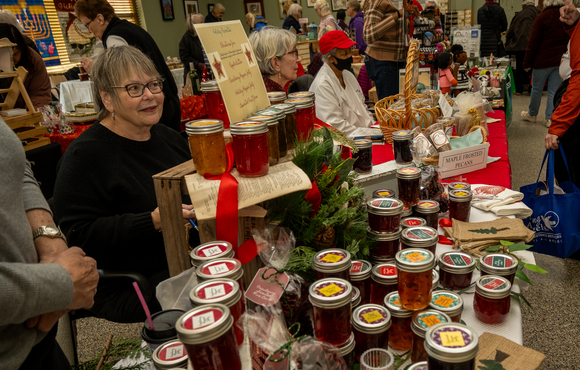Craft items and jams on a table with vendors selling.