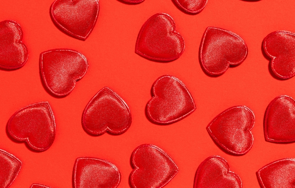 Shiny red cut out hearts on a lighter red background.