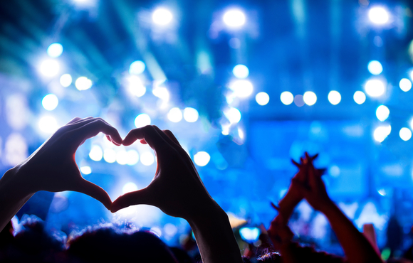 Concert background with someone making heart shape with their hands.