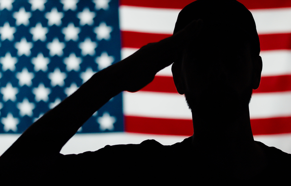 Silhouette of soldier saluting in front of American flag