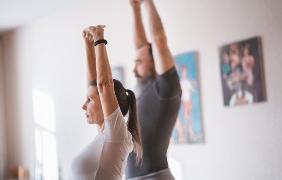 man and woman stretching with arms raised towards ceiling