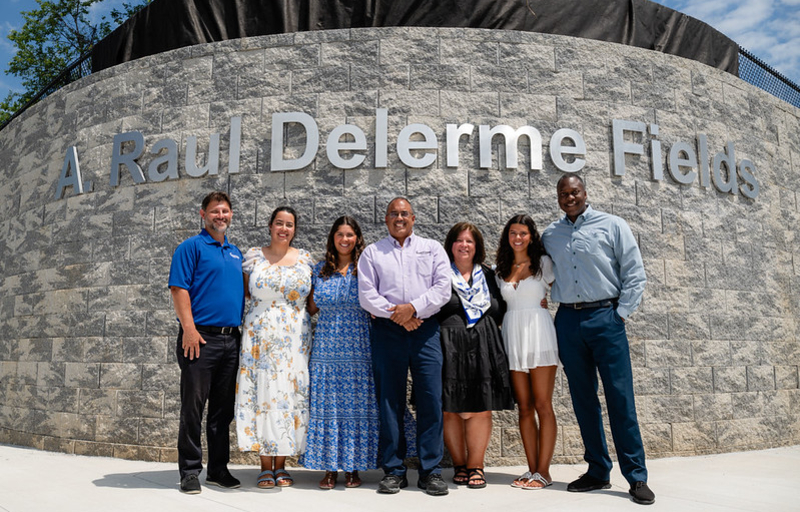 County Executive Calvin Ball posed for a photo with Raul Delerme and his family and Department of Recreation & Parks Director Nick Mooneyhan in front of the stone retaining wall at the baseball diamonds at Centennial Park West.