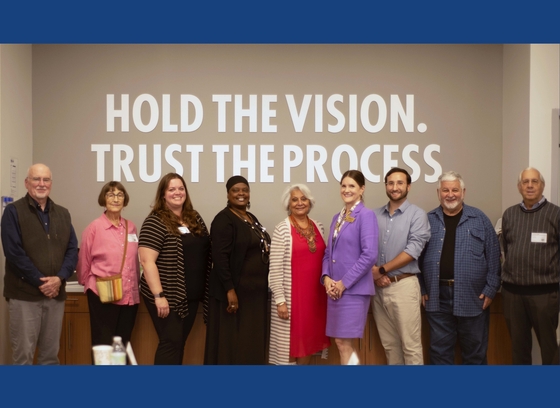 Group photo of nine of the Commission on Aging members with the words "Hold the vision, trust the process" behind them.