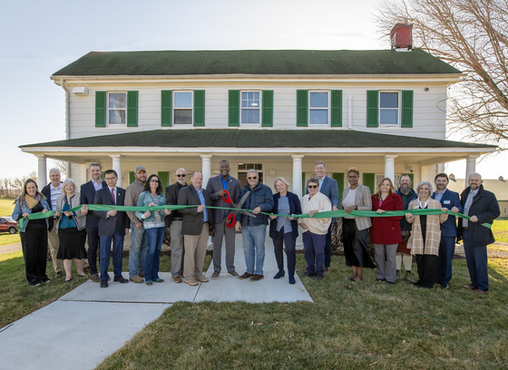 A photo of County Executive Calvin Ball and attendees cutting the ribbon in front of Hebb House to open the County's new Office of Agriculture.