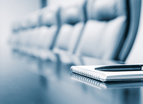 line of executive chairs at a table with a notebook and pen in the forefront