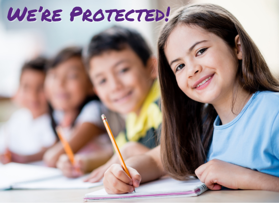 Line of school children at desks with pencils in hand the girl to the right is in clear focus the others are blurred