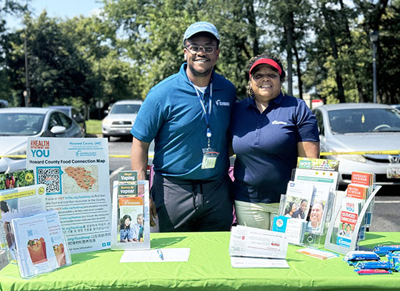 two people stand behind information table at outreach event