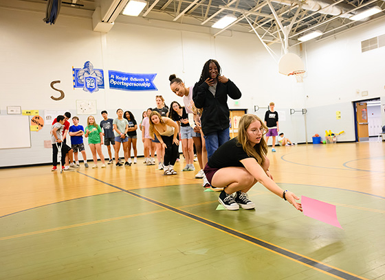 A group of junior counselors playing a game in a gymnasium.