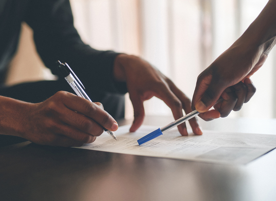 Cropped shot of an unrecognizable man filling a document with the help of a financial advisor at home