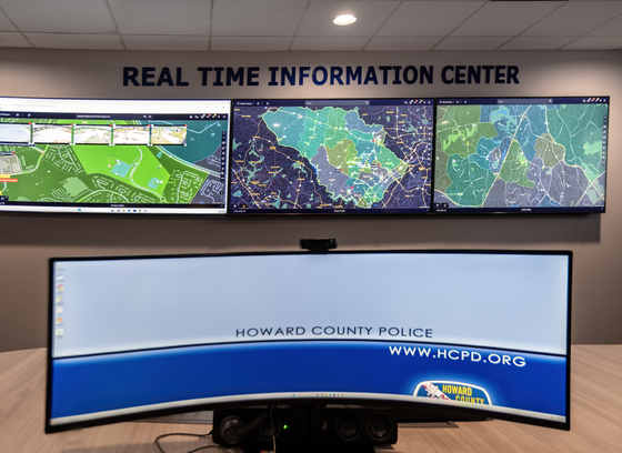 A large computer monitor in front of three tv screens showing different maps