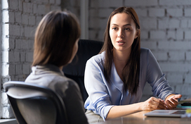 two woman talking at desk