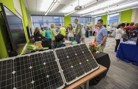 In this color photo at GreenFest 2019, attendees visit vendors in a conference room.
