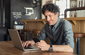 man using phone and laptop