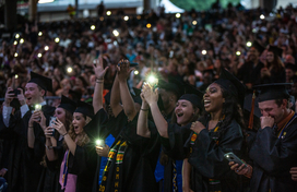 Image of high school seniors in graduation dress taking photos with their phones