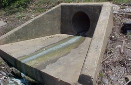 A thin stream of pollution in stormwater discharge flows over a concrete spillway.