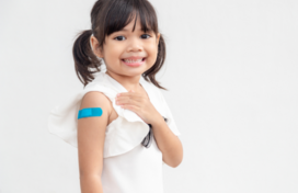 Young girl with pigtails shows the band-aid on her upper arm