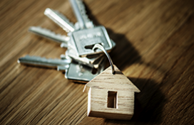 A keyring with four silver keys and a wooden charm in the shape of a house