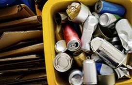 Recycled metal cans in a bin, with recycled cardboard boxes folded up next to the bin