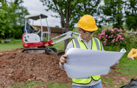 A construction worker looking at a map or blueprint